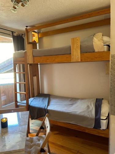 ラ・フーにあるappartement à la Foux d'Allosの二段ベッド2台とテーブルのある寝室