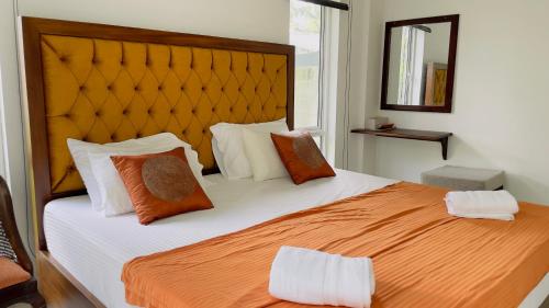 - une chambre dotée d'un grand lit avec des oreillers orange et blancs dans l'établissement Villa with a private pool and Garden-Ivory Villa Not for Local, à Kandana