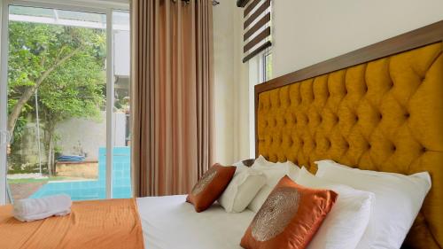 um quarto com uma cama com almofadas brancas e uma grande janela em Villa with a private pool and Garden-Ivory Villa Not for Local em Kandana