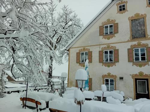 a house covered in snow in front of it at Gasthaus zur Moosmühle in Huglfing