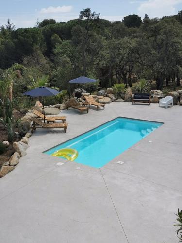 - une piscine avec deux parasols et des bancs dans l'établissement Dépendance dans Mas traditionnel avec piscine, à Argelès-sur-Mer