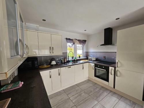 uma grande cozinha com armários brancos e uma janela em Modern Urban Haven: Stylish Getaway em Knockmore