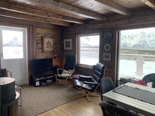 a living room with chairs and a table and two windows at Lyngen Biarnes- Nordreisa in Hamnnes