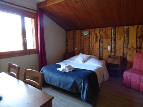 um quarto com uma cama, uma mesa e uma cadeira em Hôtel Logis La Crémaillère em Saint-Bonnet-en-Champsaur