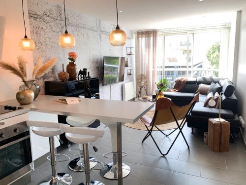 une cuisine et un salon avec une table et des chaises blanches dans l'établissement Appartement en plein centre-ville, à proximité de toutes les commodités et à seulement 500m de la mer, à La Grande Motte