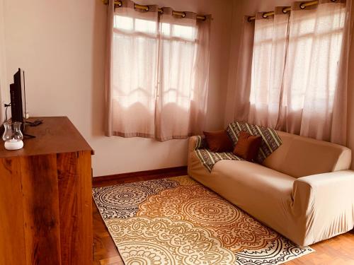 a living room with a couch and a television at Cantinho do sossego in Campos do Jordão