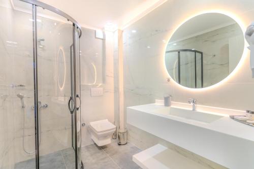 a bathroom with a shower and a sink and a mirror at Olea Suites Gemlik in Gemlik