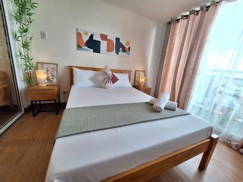 - une chambre avec un grand lit blanc et une fenêtre dans l'établissement Cozy 1BR with City and Nature View in Azure, à Manille