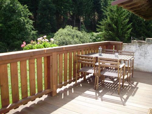 una terraza de madera con mesa y sillas. en Mühlenhof, en Stadtkyll