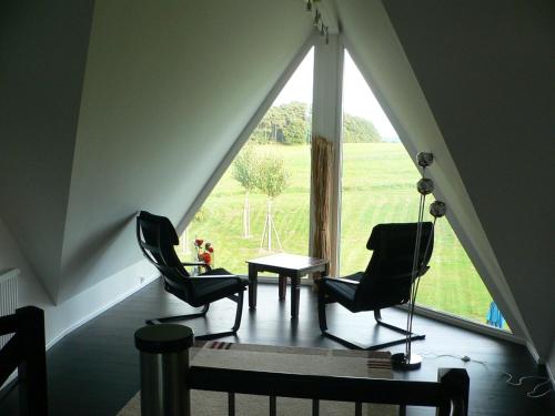 2 Stühle und ein Tisch in einem Zimmer mit einem großen Fenster in der Unterkunft Ferienhaus Sonnenpier in Putbus