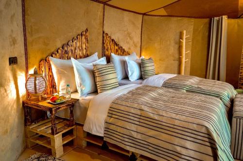 a bedroom with a large bed and a side table at Sky View Camp in Merzouga