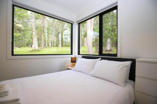 a bedroom with a bed with two large windows at Ville Views in Harrietville