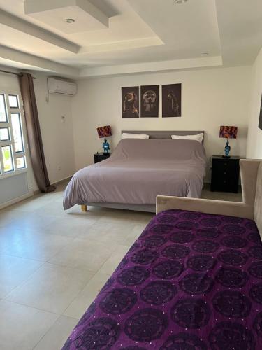 a bedroom with a large bed and a purple rug at Chez Lilie Maison d'hôtes à Saly in Saly Portudal