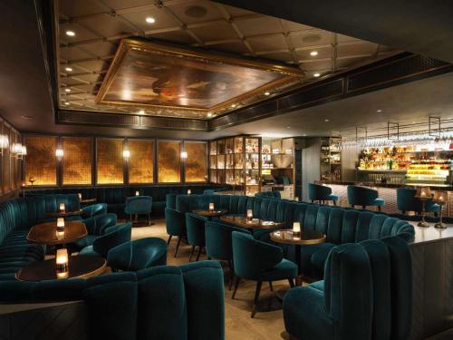 a restaurant with blue chairs and tables and a bar at Sofitel London St James in London
