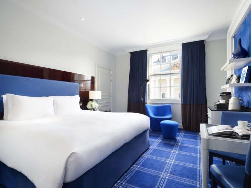 een hotelkamer met een groot bed en een stoel bij Sofitel London St James in Londen