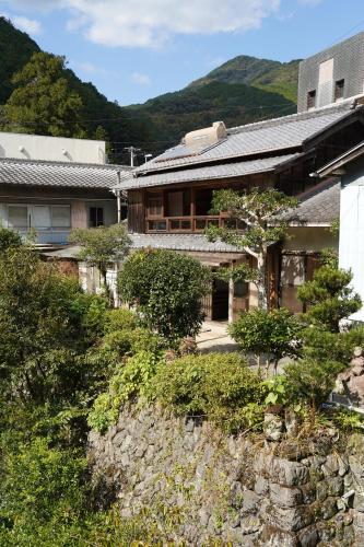 una casa en una colina con montañas en el fondo en TOSAYAMA BASE 清流沿いの里山　古民家貸切　高知市街地より車で約20分, en Kochi