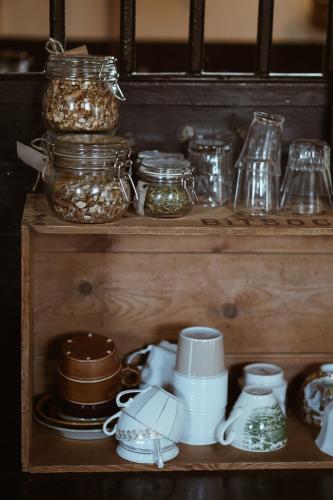 a wooden shelf with glass jars and dishes on it at Axatorpsgården in Trelleborg
