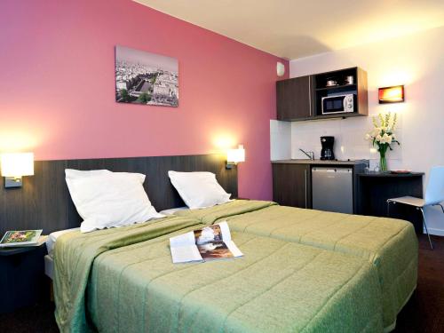ein Hotelzimmer mit einem großen Bett und rosa Wänden in der Unterkunft Aparthotel Adagio Access Paris Asnières in Asnières-sur-Seine