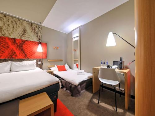 a hotel room with two beds and a desk at Ibis Gdansk Stare Miasto in Gdańsk