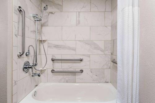 uma casa de banho com um chuveiro e uma banheira branca em Travelodge by Wyndham Dexter em Dexter