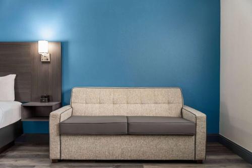 a couch in a room with a bed and a blue wall at La Quinta by Wyndham Round Rock North in Round Rock