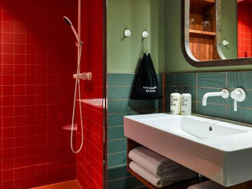 a bathroom with a white sink and red tiles at 25hours Hotel Hamburg HafenCity in Hamburg