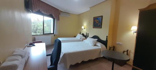 a hotel room with two beds and a couch at Hostal Almenara in Paterna del Madera