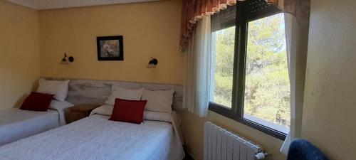 a bedroom with two beds and a window at Hostal Almenara in Paterna del Madera