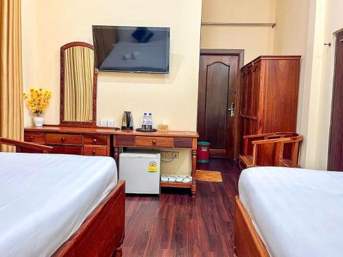 a room with two beds and a desk and a tv at HONG PEP HOTEL in Battambang