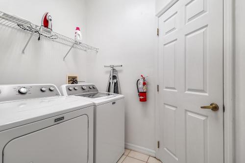 - une cuisine blanche avec un évier et un lave-linge dans l'établissement Grand Exclusive 4BR Pool Home near Disney Parks, à Davenport