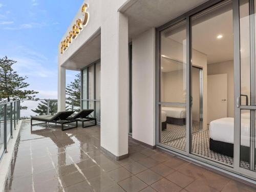 een kamer met een balkon met een bed en een slaapkamer bij Peppers Manly Beach in Sydney