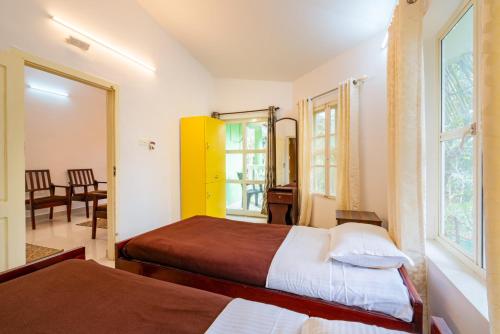 a hotel room with two beds and a window at Nature Routes Cottage in Munnar