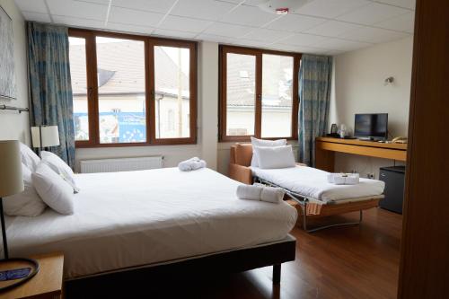 Cette chambre comprend deux lits et un bureau. dans l'établissement Le Divona, à Divonne-les-Bains