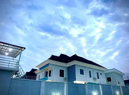 a house behind a fence with a sky at Blueprint Apartment in Akure