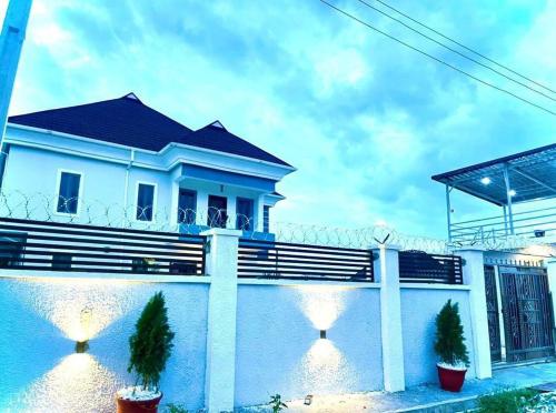 ein weißes Haus mit Topfpflanzen davor in der Unterkunft Blueprint Apartment in Akure