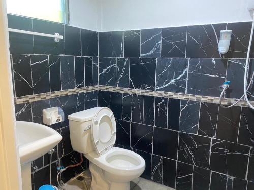 Łazienka wyłożona jest czarnymi kafelkami i dysponuje toaletą oraz umywalką. w obiekcie ทับศิลารีสอร์ท Tubsila Resort w mieście Chongsadao