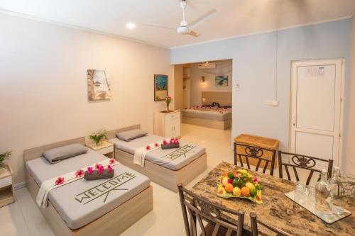 a room with three beds and a table and chairs at Dive Villa Thoddoo in Thoddoo