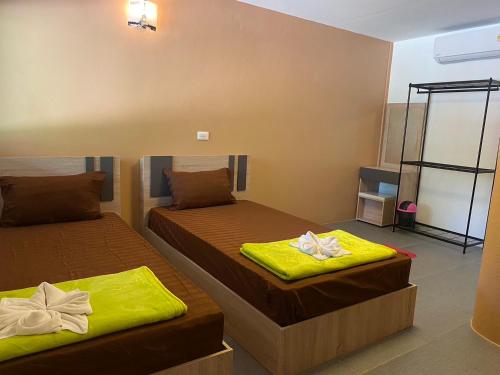 two beds in a room with yellow sheets at ทับศิลารีสอร์ท Tubsila Resort in Chongsadao