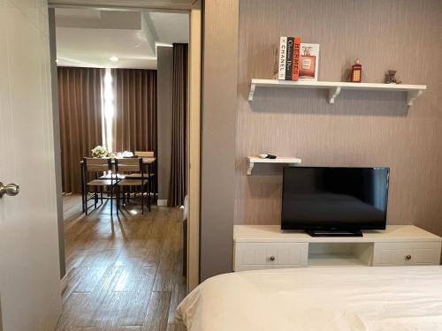 a bedroom with a television and a living room with a table at The Blu X Family grand Suite in Ban Bang Saen (1)