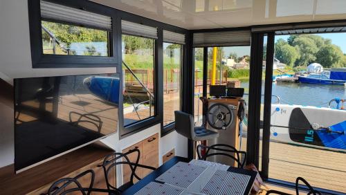Zimmer mit Fenstern und einem Tisch und Stühlen auf einem Boot in der Unterkunft Houseboat Water King apartament pływający dom na wodzie łódź Hausboot 7 os in Uraz