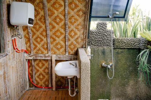 ein Bad mit einem Waschbecken und einer Dusche in der Unterkunft Alvia Joglo House & Private Pool in Tampaksiring