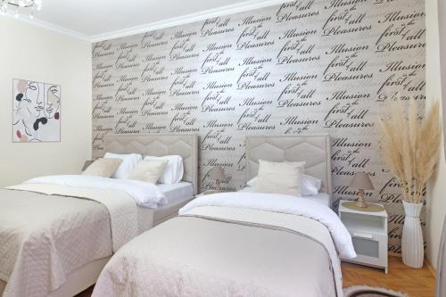 two beds in a bedroom with a wall covered in writing at Illusion Downtown Apartment in Belgrade