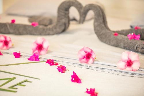 a group of pink flowers on a bed with swans at Dive Villa Thoddoo in Thoddoo