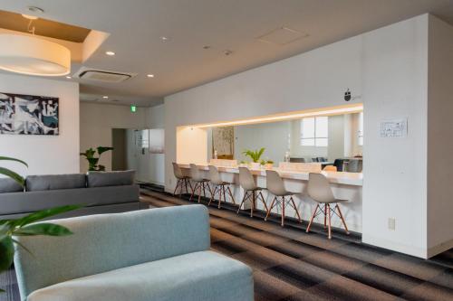 a dining room with chairs and a bar in the background at Fukuoka Share Hotel in Fukuoka