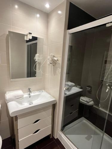 ein weißes Bad mit einem Waschbecken und einer Dusche in der Unterkunft Le Divona in Divonne-les-Bains