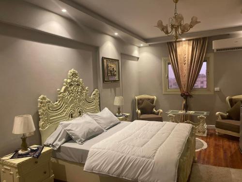a bedroom with a bed and two chairs and a window at WB Lounge - Mohandessin Apartment in Cairo