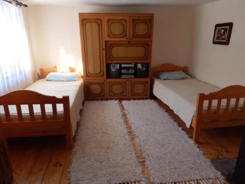 a bedroom with two beds and a cabinet and a rug at ETNO KOMPLEX NIKOLOV in Dimitrovgrad