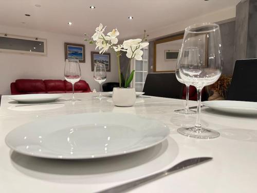 een tafel met een witte plaat en wijnglazen bij Le Contemporain, au pied de la chaîne du JURA, 3 chambres in Thoiry