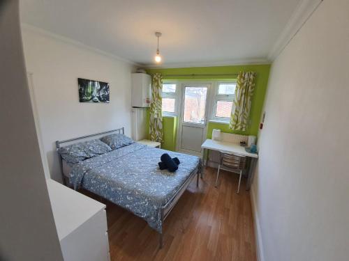 a small bedroom with a bed and a table at Eastwood Rooms in Goodmayes