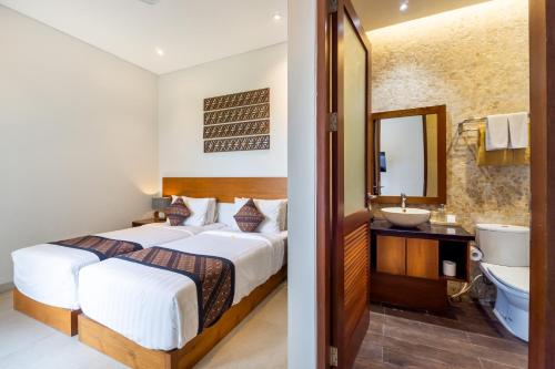een slaapkamer met een bed, een wastafel en een spiegel bij Angan-Angan Villas in Canggu